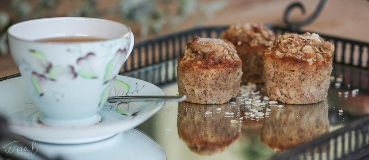 Fluffy apple muffins on a reflective tray next to a floral teacup.