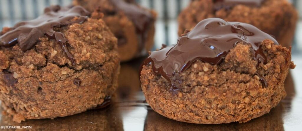 Three grain-free espresso chocolate muffins with melted dark chocolate dripping down the sides.