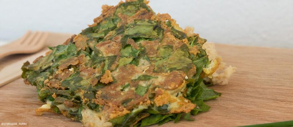 Golden-brown tuna and spinach fishcakes served on a wooden board with a light green garnish.